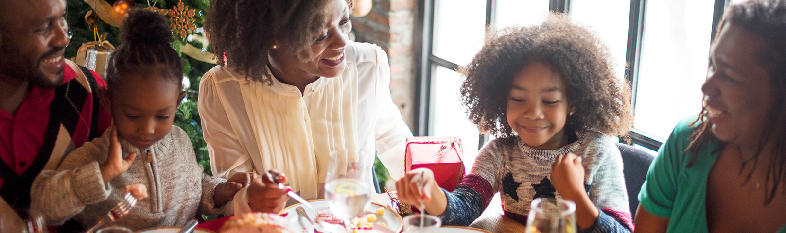 an african american woman laughs with her daughter during a holiday meal despite hearing loss